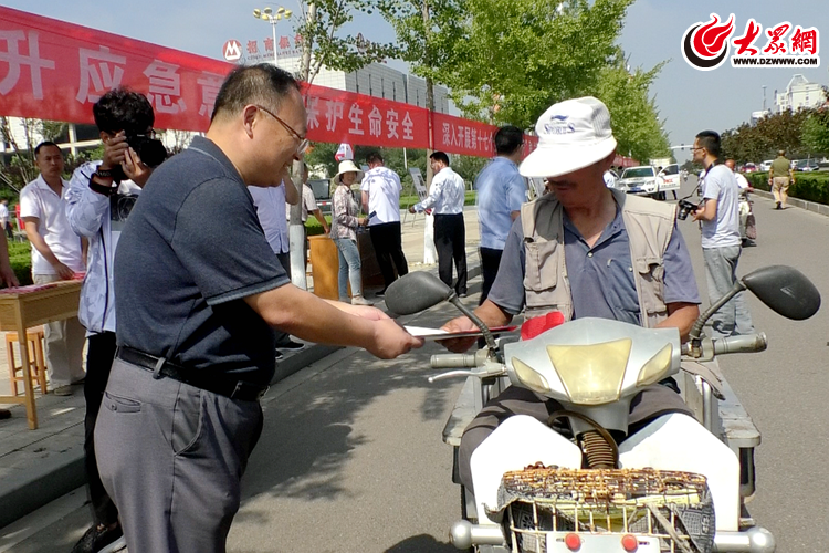 莒县人民政府党组成员吴锡华向群众发放安全知识单页